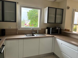 A modern kitchen with a window, a sink, cabinets, and a microwave.