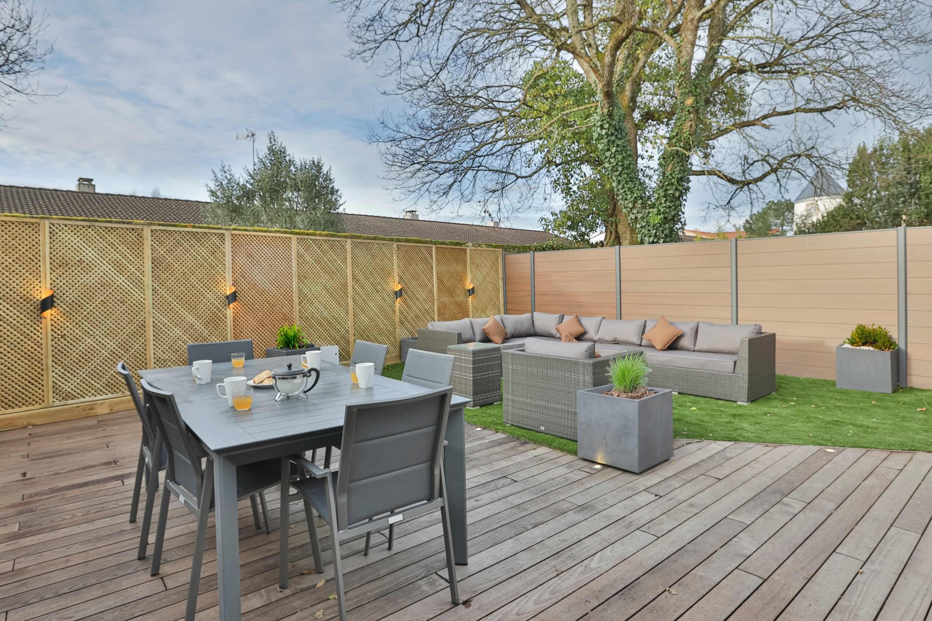 Eine Terrasse im Freien mit Esstisch, Stühlen, einer Couch und Pflanzgefäßen.