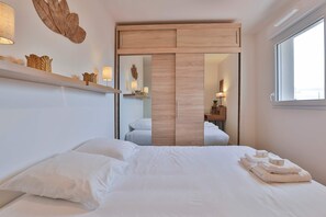 Ein Hotelzimmer mit Bett, Spiegel, Holzschrank, Ablagefläche mit Dekoration und Fenster.