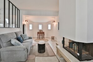 Ein modernes Wohnzimmer mit einem grauen Sofa, einem runden Couchtisch und einem Kamin.