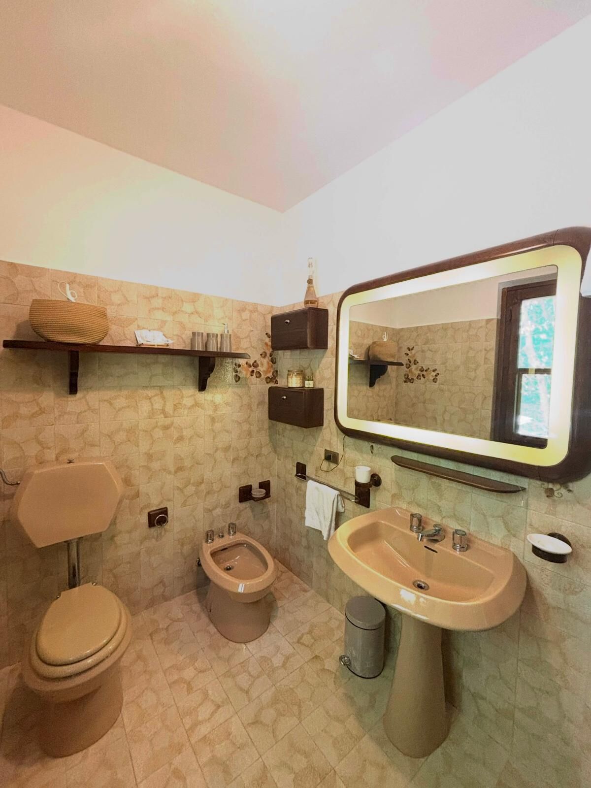 A bathroom with a toilet, bidet, sink, and mirror.