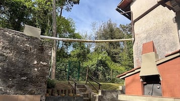 Una scala in pietra conduce a un edificio in mattoni con un camino, immerso nel verde.