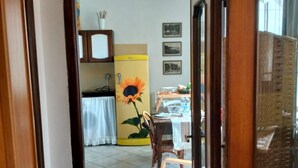 A room with a dining table, chairs, a sunflower decoration, and a refrigerator. - Studio Apartment - Corner 28 (Bolsena)