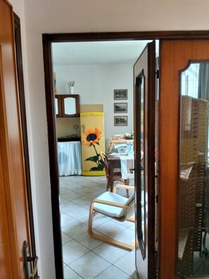 Ein Zimmer mit Esstisch, Stühlen, einer Sonnenblumen-Dekoration und einem Kühlschrank.