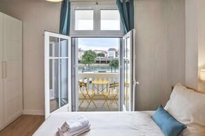 Ein Schlafzimmer mit Bett, Fenster und Balkon mit Stühlen und Tisch.