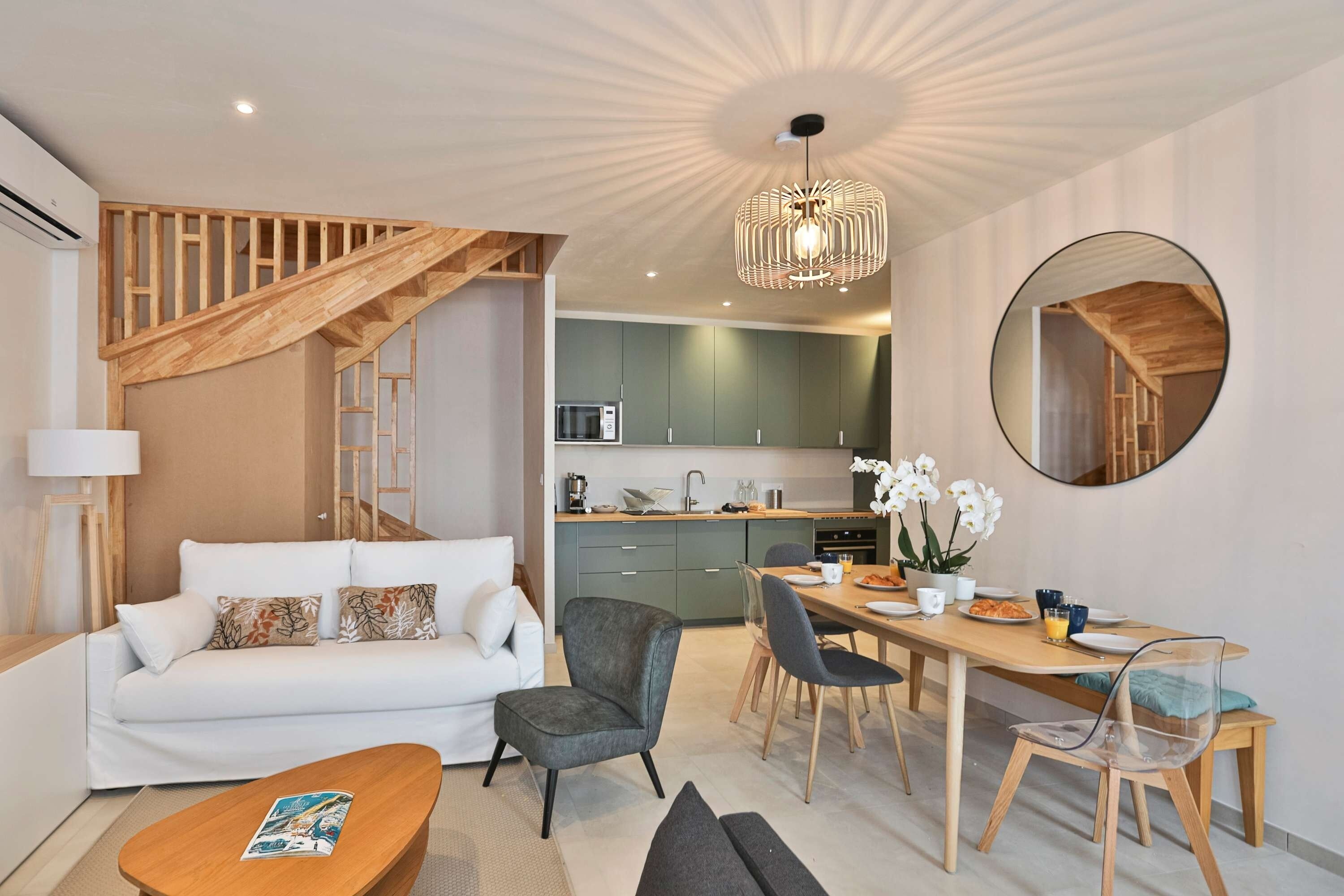 Un salon moderne avec un escalier, un coin repas et une cuisine.