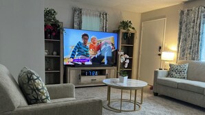 Ein Wohnzimmer mit Fernseher, einer Couch, einem Couchtisch und einem Bücherregal.