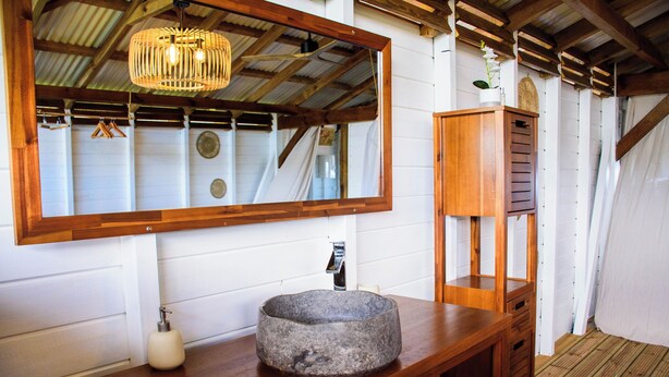 Ein Badezimmer mit einem Holzkosmetikschrank, einem Steintonne, einem Spiegel und einer Pendelleuchte.