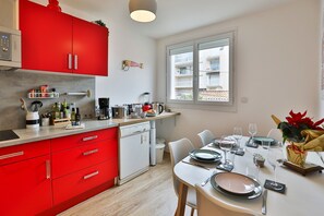 Une cuisine moderne avec des meubles rouges, un lave-vaisselle et un coin repas aménagé pour prendre un repas.