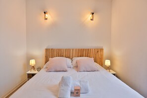 Un lit double avec deux oreillers, deux tables de chevet avec des lampes et un panneau de bienvenue posé sur le lit.