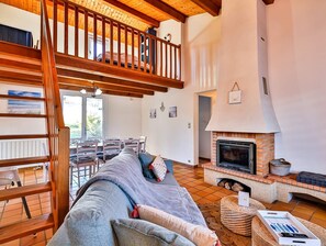A spacious living area with a high wooden ceiling, a fireplace, and a balcony overlooking a garden. - Petit Havre de paix - Three Bedroom House, Sleeps 7 (Longeville-sur-Mer)