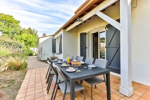 An outdoor dining area with a table set for four, surrounded by chairs, and a covered patio. - Petit Havre de paix - Three Bedroom House, Sleeps 7 (Longeville-sur-Mer)