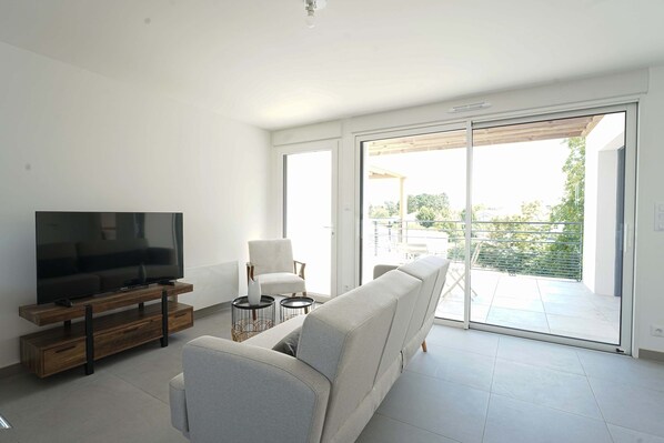 Una sala de estar moderna con un televisor de pantalla plana, un sofá, un sillón y una mesita.