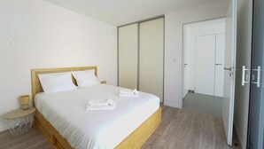 A bedroom with a bed, bedside tables, a wardrobe, and a door.