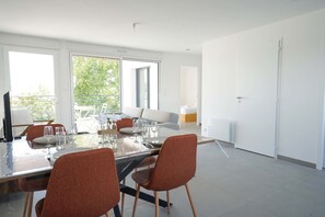 Un comedor moderno con una mesa de vidrio, sillas rojas y vistas al exterior.