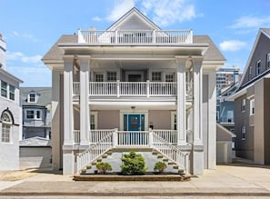 A two-story house with a front porch, a blue door, and a number '105' on the wall. - Luxury Beach Block | Sauna + Cold Plunge + Hot Tub (Ventnor City)