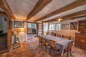 A dining area with a long table, wooden chairs, a ladder, and a staircase. - Ty Rance - Maison Avec Terrasse (Plouër-sur-Rance)