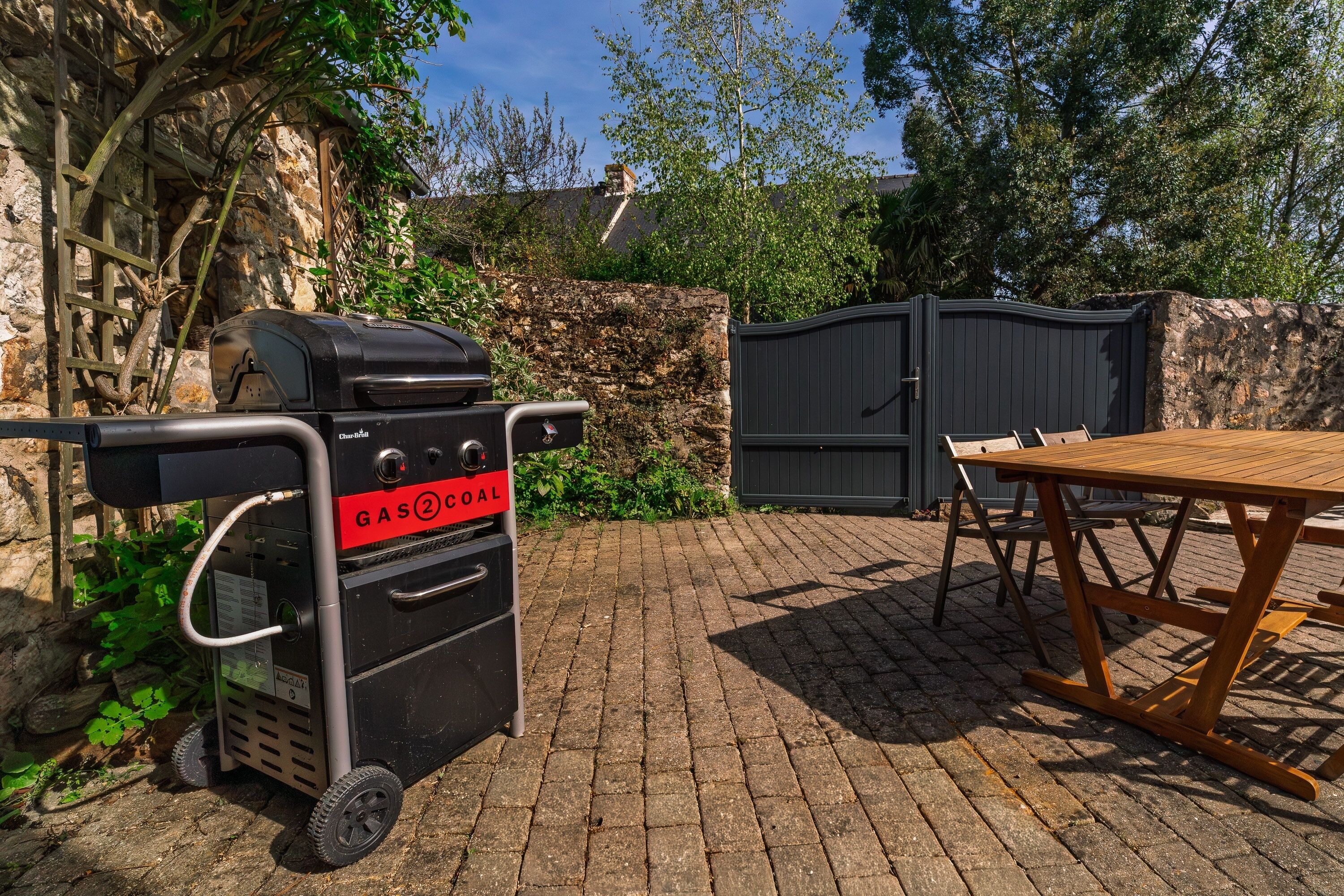 A patio with a grill, a table, and a stone wall.