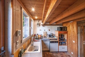 A compact kitchen with wooden beams, a sink, a microwave, and a dishwasher. - Ty Rance - Maison Avec Terrasse (Plouër-sur-Rance)
