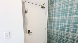 Un pasillo con una puerta blanca, un papel tapiz verde estampado y suelo de madera.