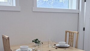 Una mesa de comedor con sillas, un florero con una planta y una ventana con vista a la montaña.