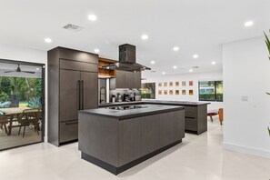 Una cocina moderna con una isla central, electrodomésticos integrados y una zona de comedor con vistas.