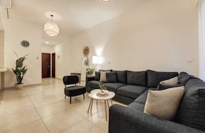 Una sala de estar moderna con un sofá modular, una mesita redonda y una planta en maceta.