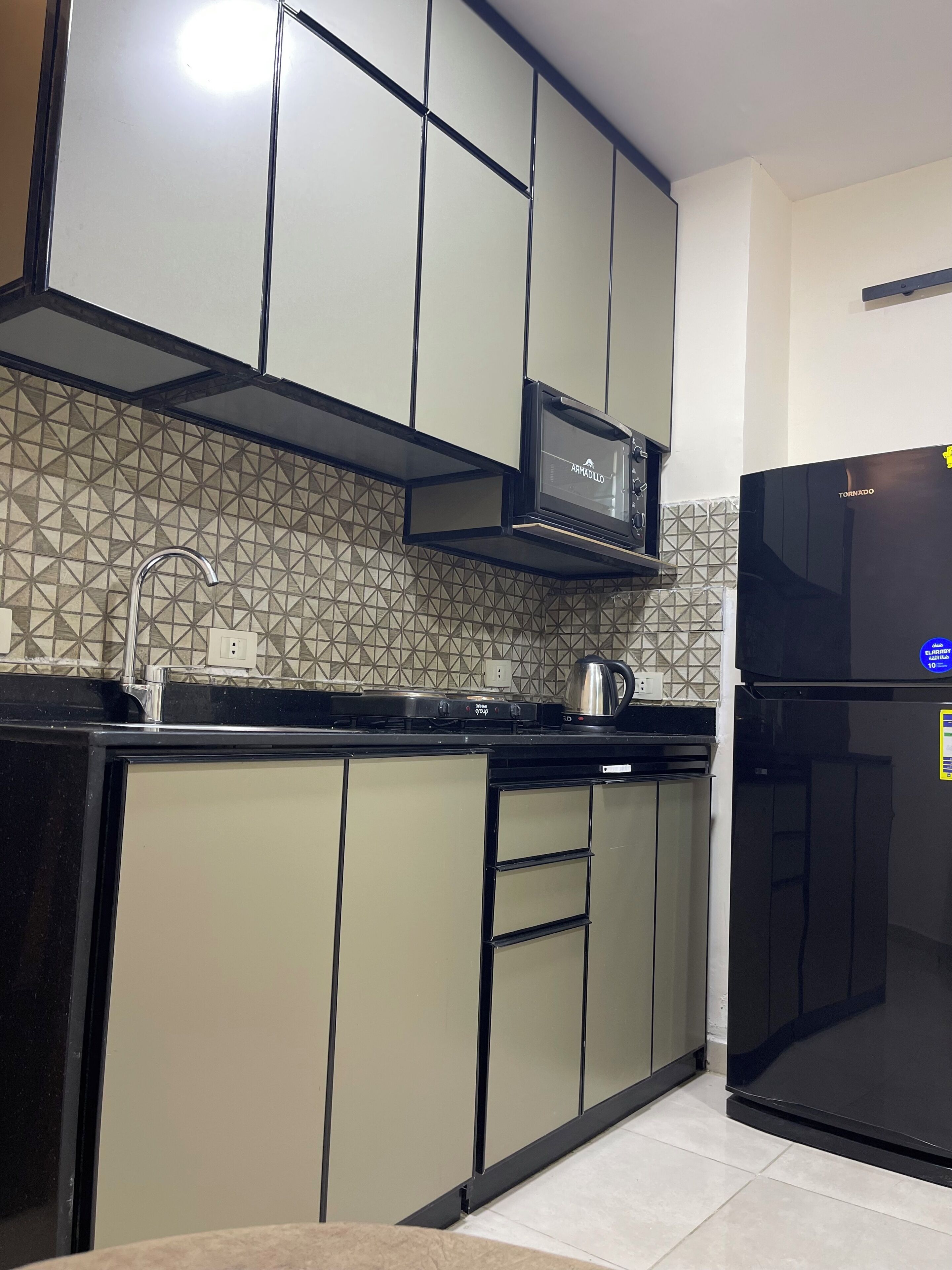 Une cuisine moderne équipée d’un four à micro-ondes, d’un réfrigérateur et d’appareils électroménagers en acier inoxydable.
