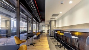 Un espace de bureau moderne avec des murs en verre, un plancher en bois et un mélange de chaises jaunes et grises.