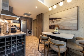 A modern kitchen with a wine rack, a dining area with chairs, and a large abstract painting on the wall. - Foreshore Luxury Place (Cape Town City Centre)