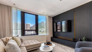 A modern living room with a sofa, coffee table, and TV. - Foreshore Luxury Place (Cape Town City Centre)
