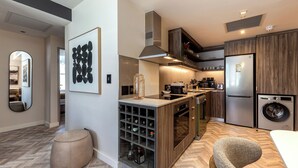 A modern kitchen with a built-in wine cooler, a stainless steel refrigerator, and a washing machine. - Foreshore Luxury Place (Cape Town City Centre)