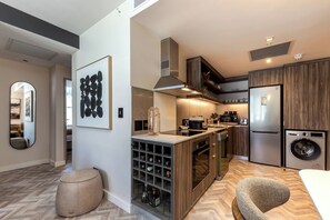 A modern kitchen with a built-in wine cooler, a stainless steel refrigerator, and a washing machine. - Foreshore Luxury Place (Cape Town City Centre)