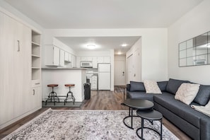Eine moderne Wohnung mit Küche, einem grauen Sofa und einem gemusterten Teppich.