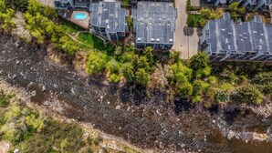 Une vue aérienne d’un complexe résidentiel comprenant plusieurs bâtiments, une piscine et une rivière.