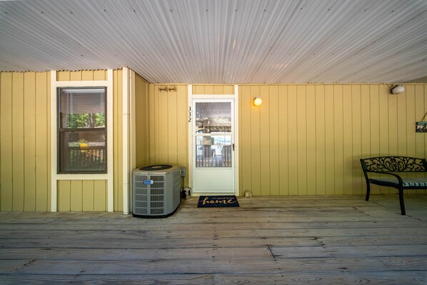 A room with a wooden floor, a door with a window, an air conditioning unit, a bench, and a welcome mat. - Lakefront Getaway at Bay Point Village (Osage Township)