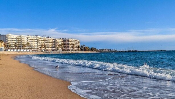 Uma praia com um hotel ao fundo.