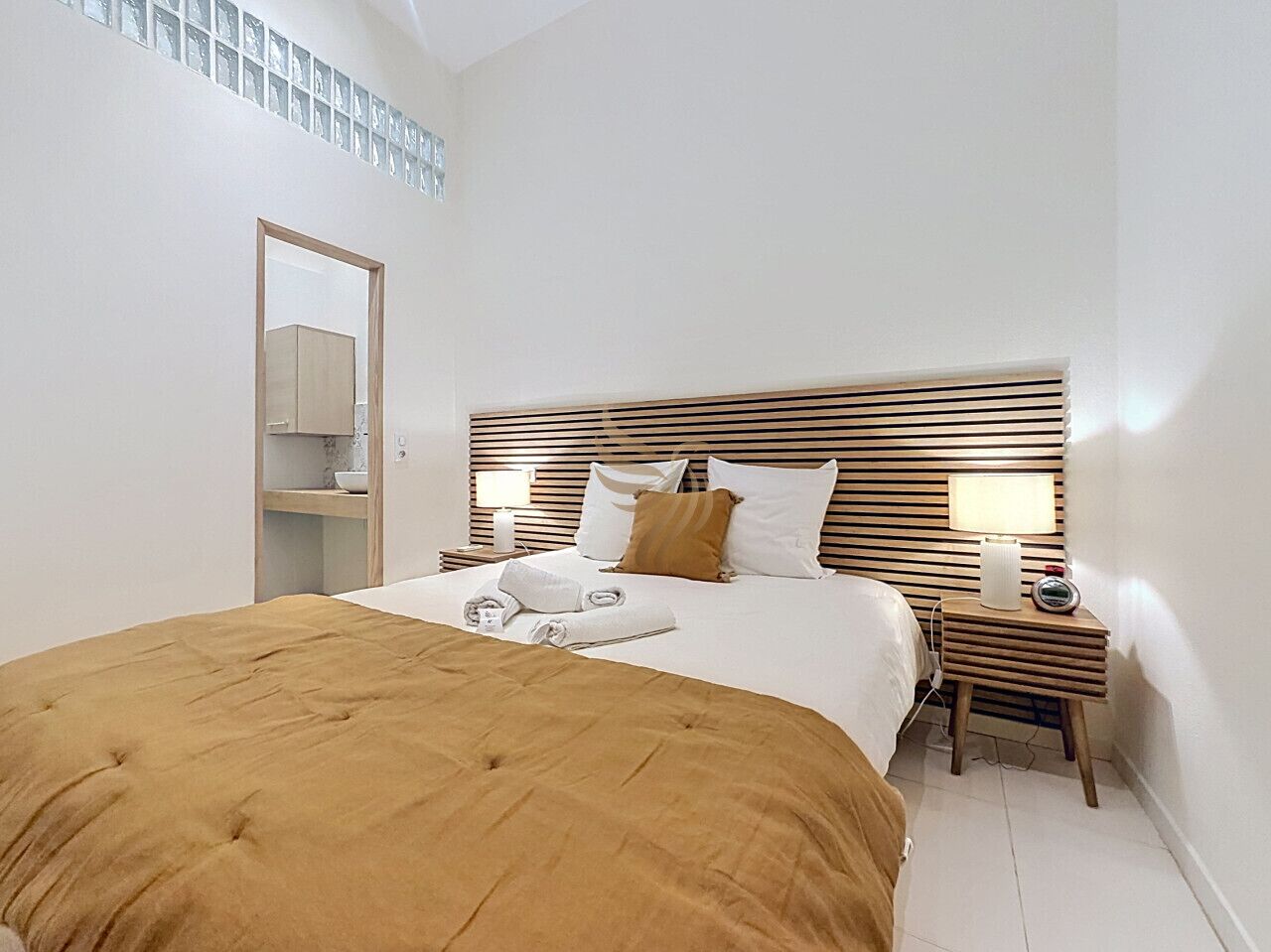 Een hotelkamer met een bed, nachtkastjes, een spiegel en een wandplank.