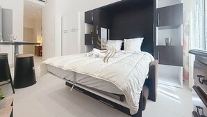 Quarto moderno com cama, mesas de cabeceira e roupeiro embutido.