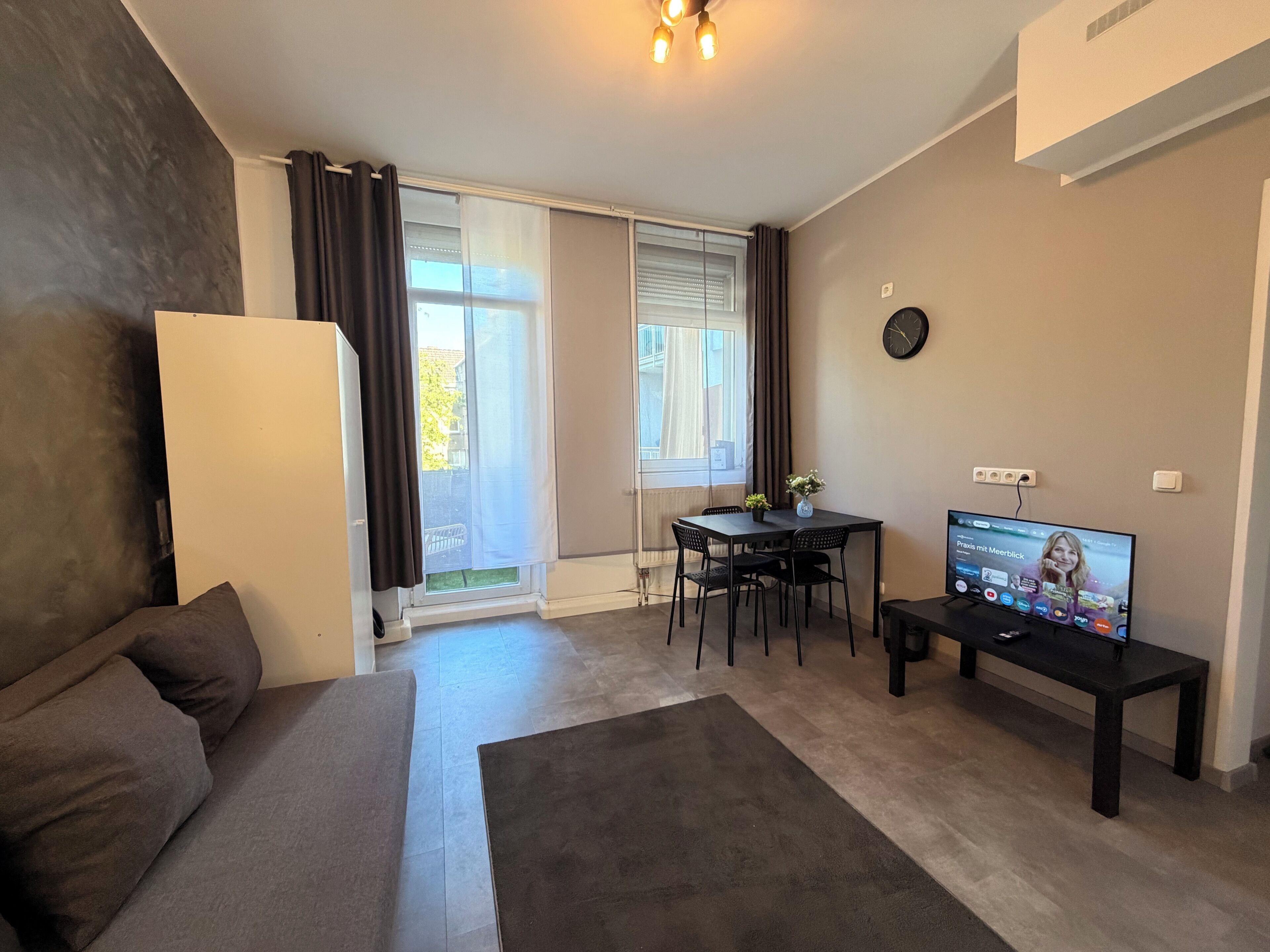 Ein modernes Wohnzimmer mit einer Couch, einem Esstisch und einem Fernseher.