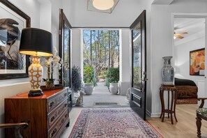 En gang med et mønstret tæppe, en lampe og en vase på et bord.