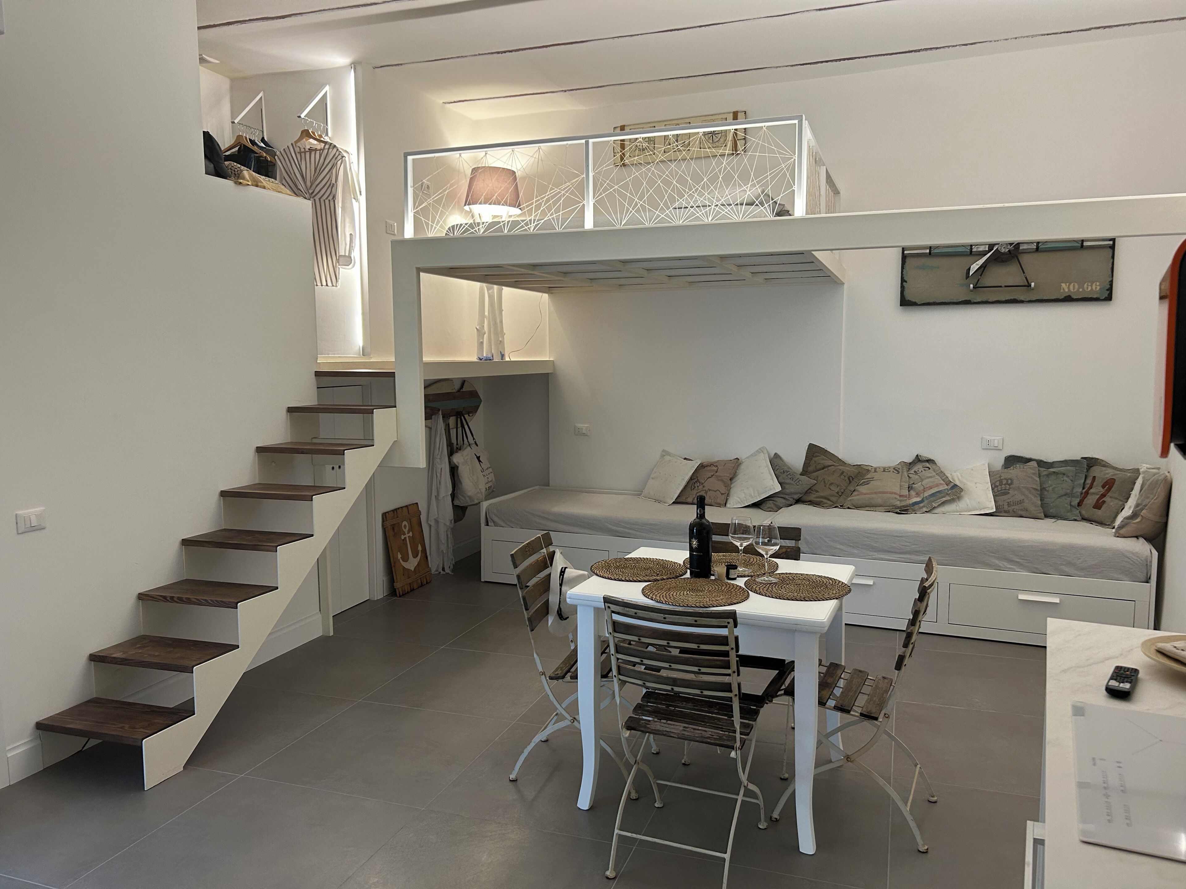 Ein kompakter Wohnraum mit Etagenbett, Essbereich mit Tisch und Stühlen sowie einer Treppe.