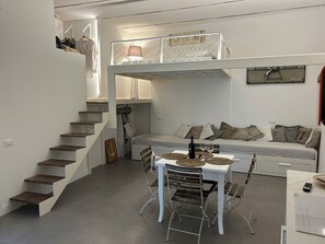 A compact living space with a bunk bed, a dining area with a table and chairs, and a staircase. - Le Petit | Luxury Loft in the Heart of Sperlonga - Easy Access (Sperlonga)