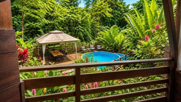 A wooden deck with a pool, surrounded by lush greenery and a gazebo. - Casa Toucan - Jungle Pool Villa - Private Pool -  Starlink - Quads (Isla Colon)