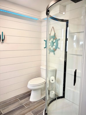 Ein modernes Badezimmer mit Duschkabine aus Glas, einer weißen Toilette und einer Schiffsluder-Dekoration.