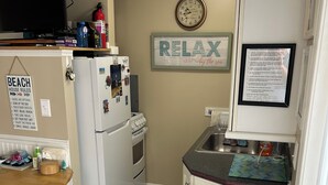 A compact kitchen with a refrigerator, a sink, a microwave, and a small dining table.
