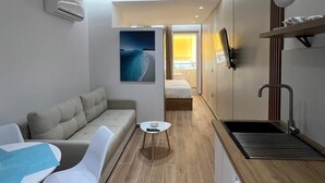 Camera d'albergo compatta con divano, tavolo da pranzo, sedie, tavolino e bagno con doccia.
