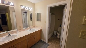 Une salle de bain avec deux lavabos, un miroir avec éclairage intégré, une douche et des toilettes.
