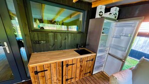 Eine kleine Küche mit einer Holz Arbeitsplatte, einem Spülbecken und einem integrierten Kühlschrank.