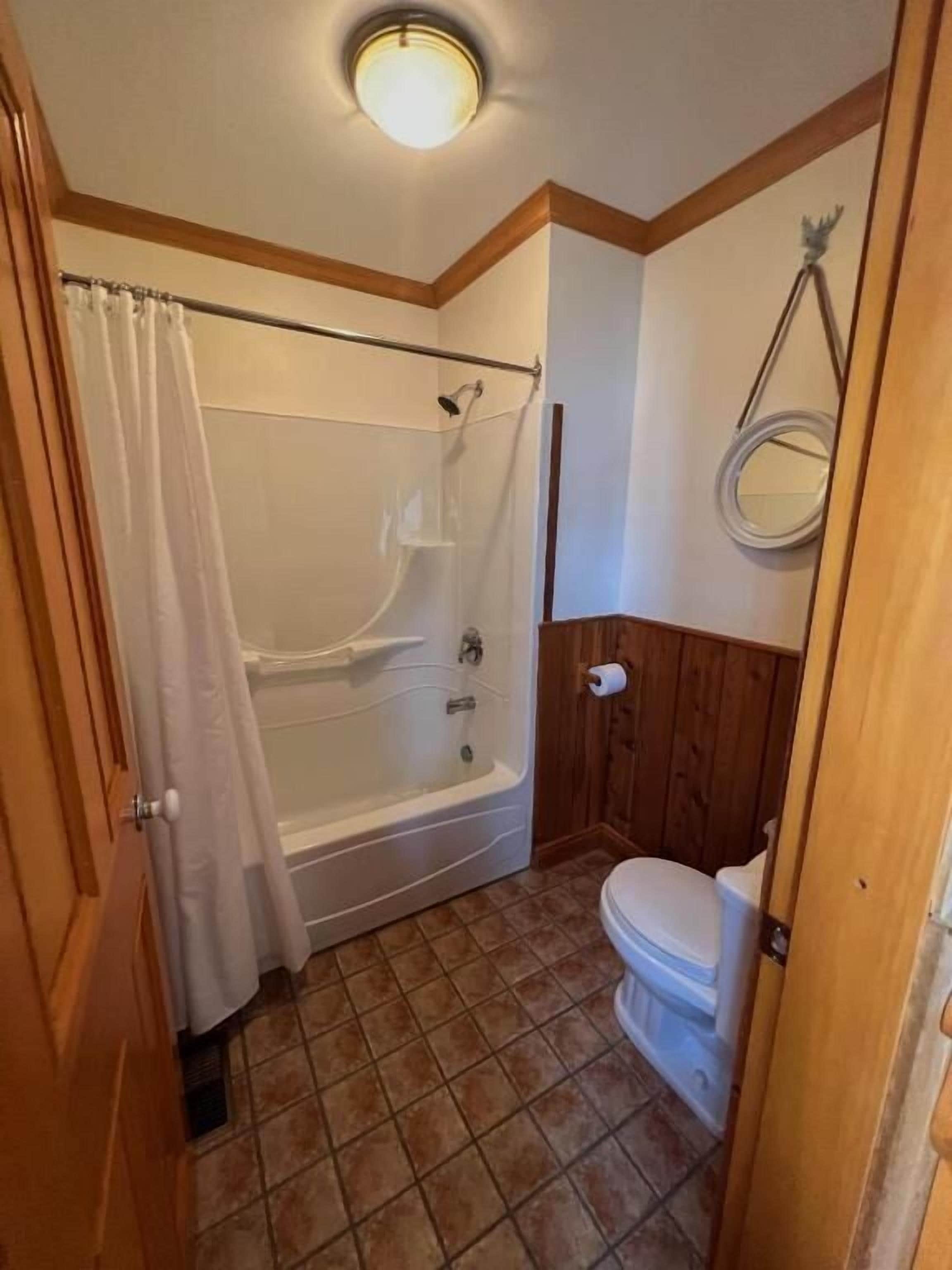 A bathroom with a bathtub, toilet, and shower curtain.
